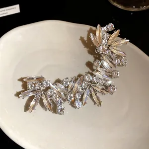 Primo piano dettagliato di un lussuoso ear cuff irregolare con cristalli brillanti.