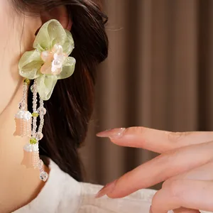 Detail view of green chiffon flower earrings with hanging beads and resin floral center.