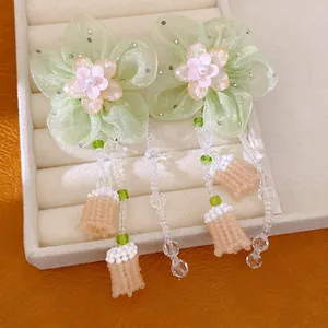 Detail macro view of light green chiffon flower earrings with elegant beaded tassels