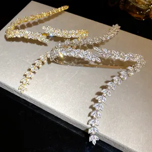 Close-up of leaf-shaped zircon cuff bracelets in gold and silver finish with sparkling stones.