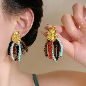 Close-up detail of vintage golden leaf earrings featuring vibrant colorful beaded tassels.