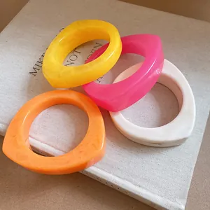 Detailed macro shot of four colorful geometric marbled resin curved bracelets on a book