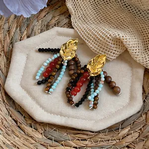 Macro detail of vintage ethnic leaf earrings with colorful wooden and glass bead tassels