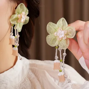 Close-up of handmade forest style chiffon flower earrings with elegant dangling bead tassels.