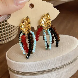 Close-up of vintage leaf earrings with colorful glass and wooden bead tassels