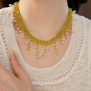 Detail of bohemian woven bead necklace with green net and pink flower fringes