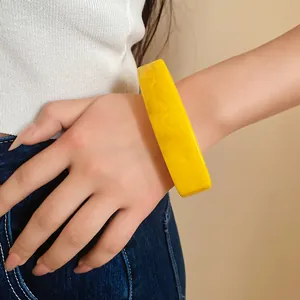 Close-up of a vibrant yellow curved resin bangle with unique marbled ink-wash patterns.