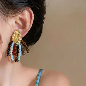 Detailed view of vintage leaf earrings with colorful wooden and glass bead tassels.