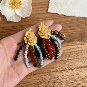 Detailed view of vintage leaf earrings with colorful glass and wooden bead tassels.