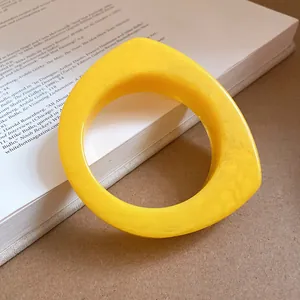 Detailed view of a geometric yellow resin bangle bracelet with unique marbled texture