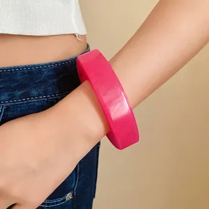 Close-up view of a vibrant pink geometric resin bangle bracelet worn on a female wrist