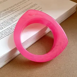 Close-up of a pink marbled resin geometric bangle with irregular curved design
