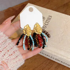 Close-up of vintage leaf tassel earrings featuring glass and colorful wood beads