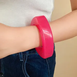 Close-up detail of a bright pink chunky resin geometric bangle bracelet worn on a wrist.
