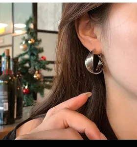 Detail view of stylish silver textured metal hoop earrings for women worn on the ear