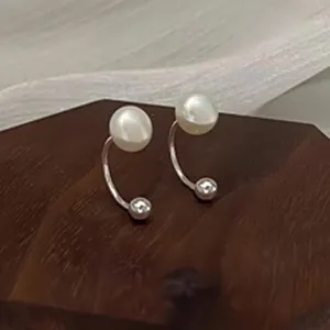 Elegant S999 sterling silver pearl earrings with zircon detail on a wooden display stand