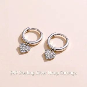 Close-up of 999 sterling silver heart earrings with sparkling zircon inlay