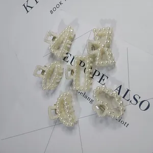 Macro shot of various elegant white pearl-embellished hair claw clips for women.
