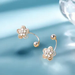 Close-up of S999 silver flower earrings featuring zircon-studded petals on blue silk