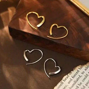 Close-up macro view of minimalist heart-shaped hoop earrings in polished gold and silver finish