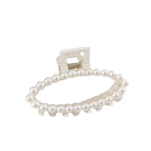 Elegant oval faux pearl hair claw clip with metallic spring mechanism for women.