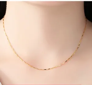 Detailed close-up of a slim gold-plated clavicle chain necklace worn on a woman's neck