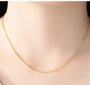 Detailed macro view of a 14K gold plated box chain necklace worn gracefully on the neck