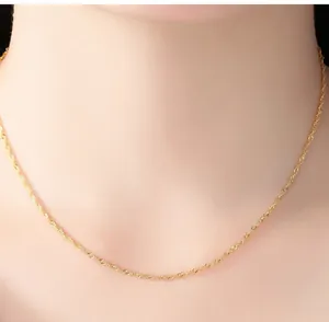 Detailed close-up of a delicate golden water wave chain necklace on a model's neck