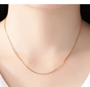 Detailed close-up view of elegant 14K gold plated snake chain necklace on model neck