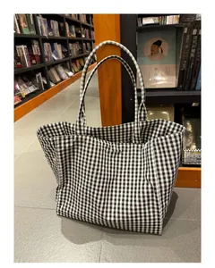 Detailed view of a large black and white gingham checkered tote bag in a library setting