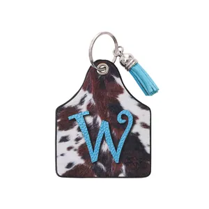 Vintage western farm ear tag keychain with cow print leather and blue letter W design
