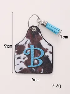 Detailed size view of a cow print leather ear tag keychain with blue tassel