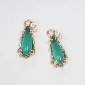 Detailed view of green teardrop glass pendants with gold-plated copper and cubic zirconia.