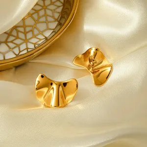 Detail shot of irregular golden stainless steel earrings on elegant silk fabric