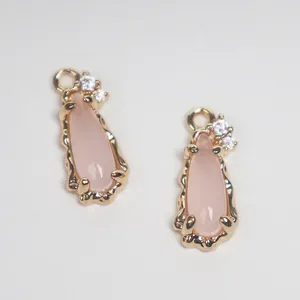 Close-up of pink teardrop glass pendant with copper-set clear zircons for jewelry.