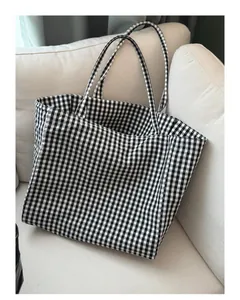 Stylish large black and white gingham tote bag displayed on a minimalist white sofa.