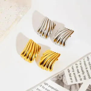 Macro view of gold and silver ribbed shell earrings on minimalist white surface