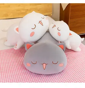 Close-up of cute peach cat plush pillows in grey and white colors displayed on a pink bed.