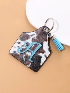 Detail view of western style cow print leather ear tag keychain featuring blue letter A