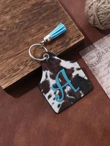 Detailed view of western cattle tag keychain with cowhide print and blue tassel.
