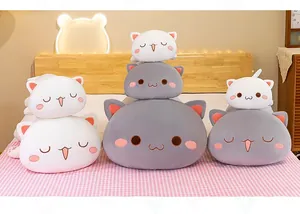 Detailed view of stacked cute grey and white cat plush pillows in a cozy bedroom setting