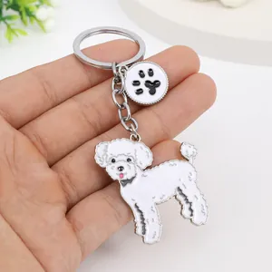 Close-up of a cute white enamel poodle keychain with a silver-tone paw print charm detail