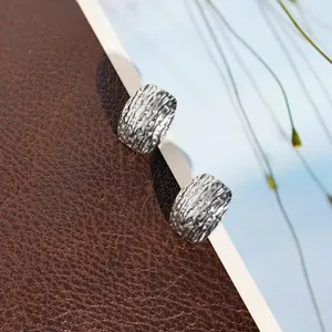 Detailed macro view of 304 stainless steel earrings featuring an irregular hammered texture.