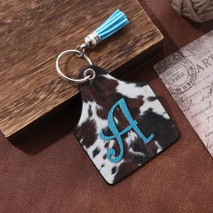 Western style cowhide print ear tag keychain featuring a blue letter A and tassel