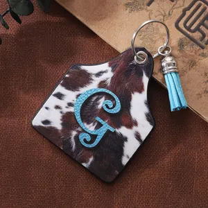 Vintage western cattle tag leather keychain featuring cow print and a blue tassel charm