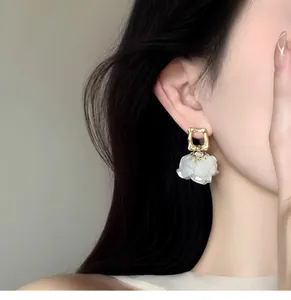 Detailed view of French petal pearl drop earrings with gold square studs on female model