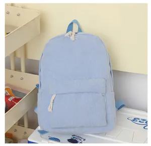 Close-up view of a light blue corduroy school backpack with textured fabric and front pocket