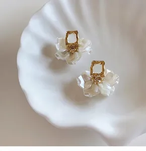 Close-up detail of elegant French style petal earrings featuring gold frames and white petals