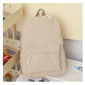 Detailed view of a vintage cream corduroy backpack featuring tassel zipper pulls
