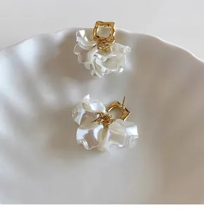 Close-up of elegant French-style petal pearl stud earrings in gold finish and white petals
